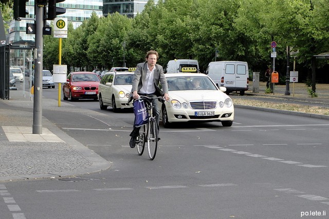 Мужчина в костюме едет на велосипеде по Берлину